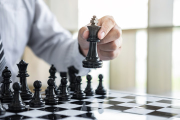 Black and White chess with player, Hands of businessman thinking to moving chess figure in competition and planning strategy to success play for win