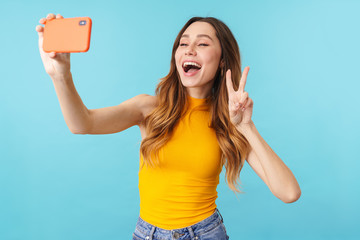 Wall Mural - Portrait of joyous woman smiling and taking selfie photo on cellphone