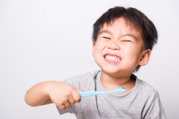 Closeup Asian face, Little children boy hand holds toothbrush he brushing teeth myself