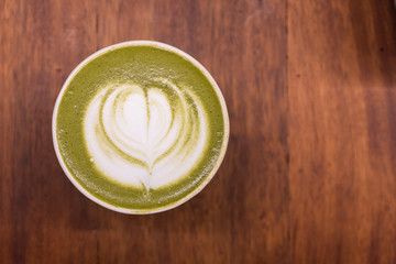 Coffee cup with Green Matcha latte art foam on wood table in coffee shop with copy space.Coffee is one of the most popular beverages.Improve Energy Levels and Burn Fat