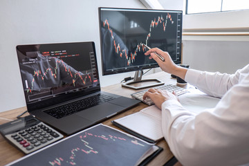 Wall Mural - Stock exchange market concept, Business investor trading or stock brokers having a planning and analyzing with display screen and pointing on the data presented and deal on a stock exchange