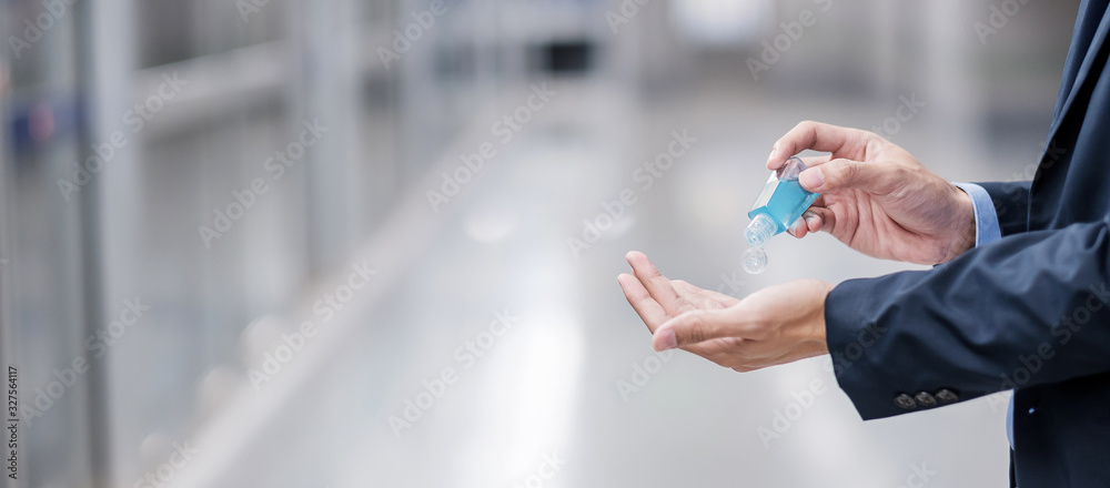 man hands using wash hand sanitizer gel dispenser, against Novel coronavirus or Corona Virus Disease (Covid-19) at public train station. Antiseptic, Hygiene and Healthcare concept - obrazy, fototapety, plakaty 