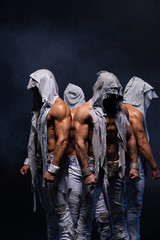 Four muscular gothic man standing shirtless on black background. Concept of mystery and secret