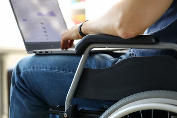 Man sitting in wheelchair working with laptop computer