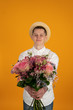 © Ivan - Smiling young man in hat holding flowers isolated on yellow background