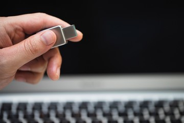 image of hand inserting usb flash drive into computer laptop.