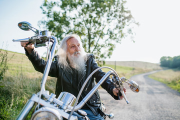 A senior man traveller with motorbike in countryside.