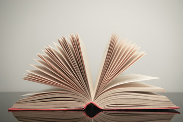 Poster - Beautiful open book on a gray and glass table background.