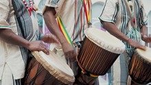 African Drummers In Ethnic Clothes Playing On Djembe Drum Close Up. Musician Beats Rhythm On African Drums. Black Artists Hit The Drums With Their Hands