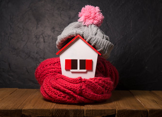 Wall Mural - house in winter - heating system concept and cold snowy weather with model of a house wearing a knitted cap