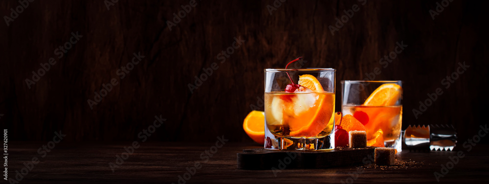 Alcoholic old fashioned cocktail with orange slice, cherry and orange peel garnish - obrazy, fototapety, plakaty 