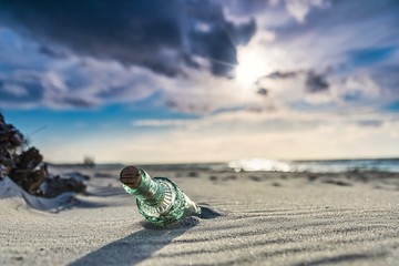 Wall Mural - message in a bottle on the beach - old glass bottle with a message on the beach with dramatic sunset on the baltic sea