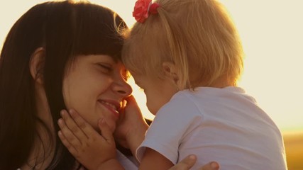 loving mother and happy little daughter have fun outdoors at sunset. the family enjoys the weekend, 
