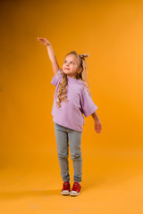 Wall Mural - portrait of a happy child girl isolate on a yellow background, space for text