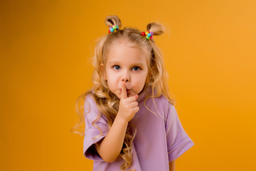 Wall Mural - portrait of a happy child girl isolate on a yellow background, space for text