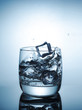 Ice cubes splashing into glass of water
