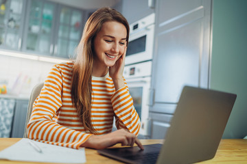 happy young freelancer woman working at home using modern laptop device, cheerful student girl in ca