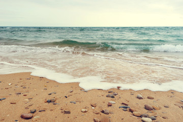 soft wave of the atlantic ocean with foam over a beach with sand and stones - calm, cloudy and lonely afternoon wallpaper