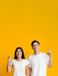 Excited asian man and woman pointing upwards