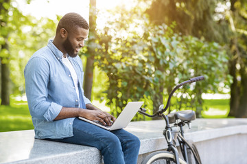 Free Wifi Spot. Young Black Man Working On Laptop In Park