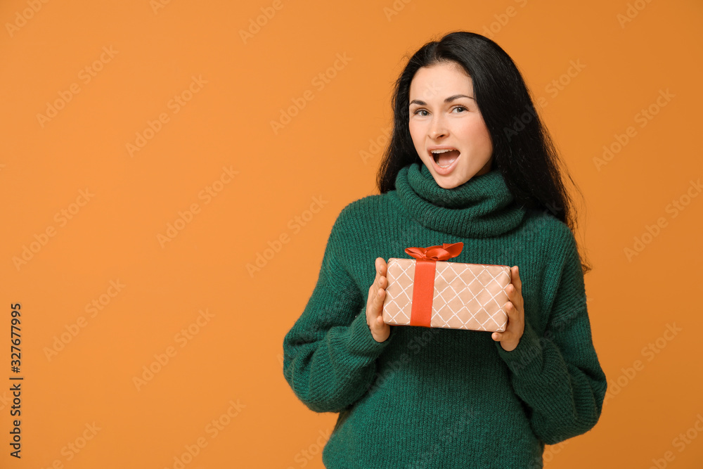 Beautiful young woman with gift on color background