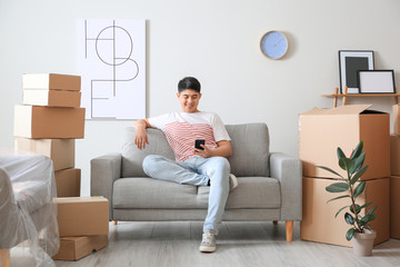 Wall Mural - Asian man sitting on sofa after moving to new house