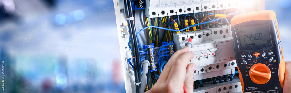 Electrician engineer installing and test electric connection wires of fuse switch box. - obrazy, fototapety, plakaty 
