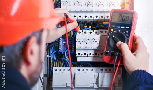 Fotomural Electrician installing electric cable wires of fuse switch box.
