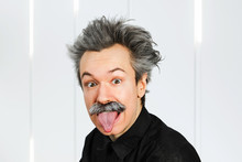 Portrait Of Jocular Aging Man With Grey Long Hair Sticking His Tongue Out In Einstein Manner