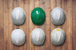 White and green safety hard hat hang on wooden wall.
