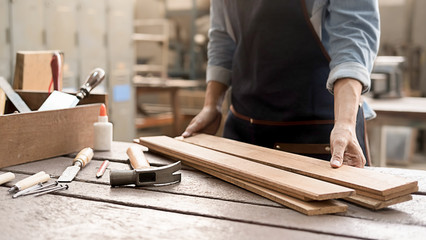 Wall Mural - Carpenter working with equipment on wooden table in carpentry shop. woman works in a carpentry shop.