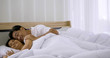 © ronnarong - Happy asian couple sleeping together in a bedroom.