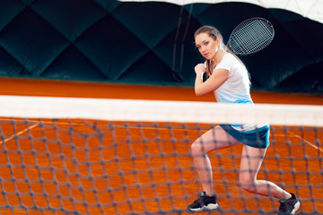 Wall Mural - Attractive woman tennis player waiting for service at indoor court