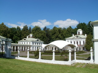 Wall Mural - An ensemble of old stone white two storey buildings with covered passages with columns and a tent in the middle against the blue sky