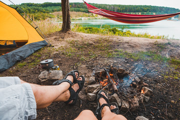 Wall Mural - couple sitting near camp fire with beautiful view of lake