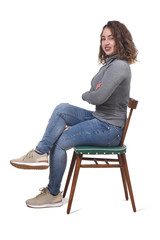 Wall Mural - portrait of a woman sitting on a chair in white background,looking at camera and legs and arms crossed