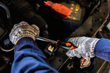 Close up, Asian man auto mechanic using a wrench and screwdriver to working service car in garage.