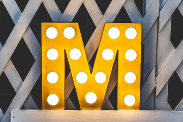 Letter M with light bulbs. Yellow decorated letter