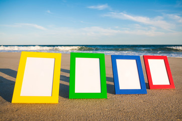 Wall Mural - row of simple colorful photo frames with blank image space lined up in the sun on an empty beach