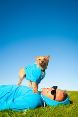 Wall Mural - Man relaxing with best friend dog in matching blue hoody sweatshirts on bright green grass meadow