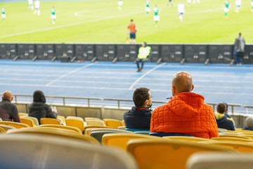 Wall Mural - spectators watch football in a half-empty stadium