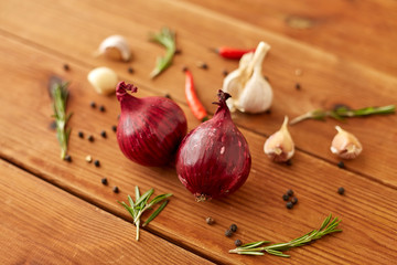 Wall Mural - food, culinary and healthy eating concept - red onion, garlic, chili pepper and rosemary on wooden table