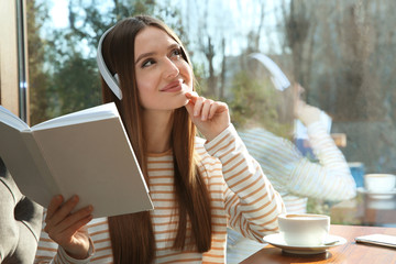 Sticker - Woman listening to audiobook at table in cafe