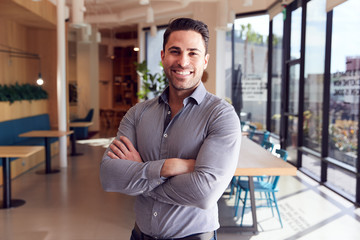 Portrait Of Businessman Standing In Modern Open Plan Office