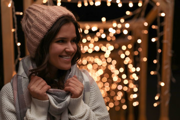 Sticker - Young woman wearing warm sweater, hat and scarf  outdoors at night. Winter season