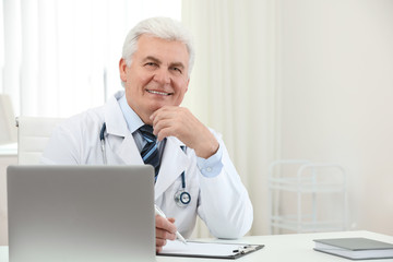 Canvas Print - Portrait of senior doctor in white coat at workplace