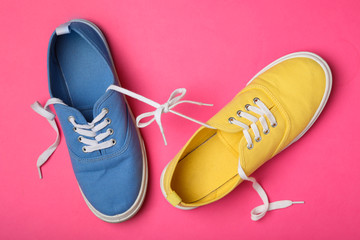 Wall Mural - Shoes tied together on pink background, flat lay. April Fool's Day