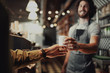© StratfordProductions - Closeup of waiter hand serving a cup of cold coffee to customer at counter in cafe
