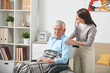 © pressmaster - Careful young nurse talking to elderly man in wheelchair while visiting him at home