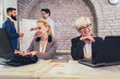 © Mediteraneo - Senior and young colleagues women sitting in modern office using laptop.